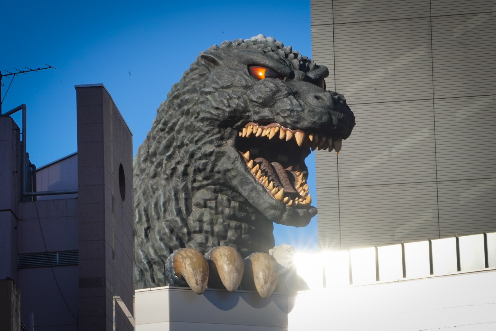 Cabeza de godzilla con boca abierta y ojos rojos mostrando los dientes